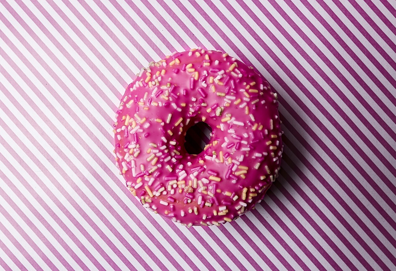 pink frosting donut on pink striped background