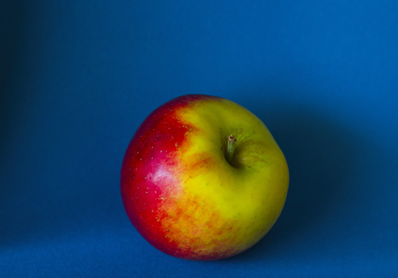 greenish red apple on a blue background