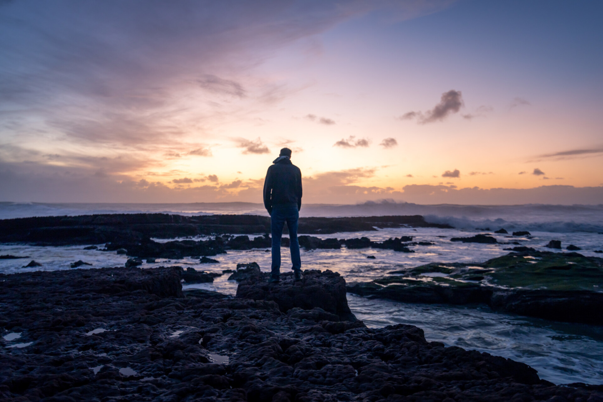 Man looks out to sea towards the sunset