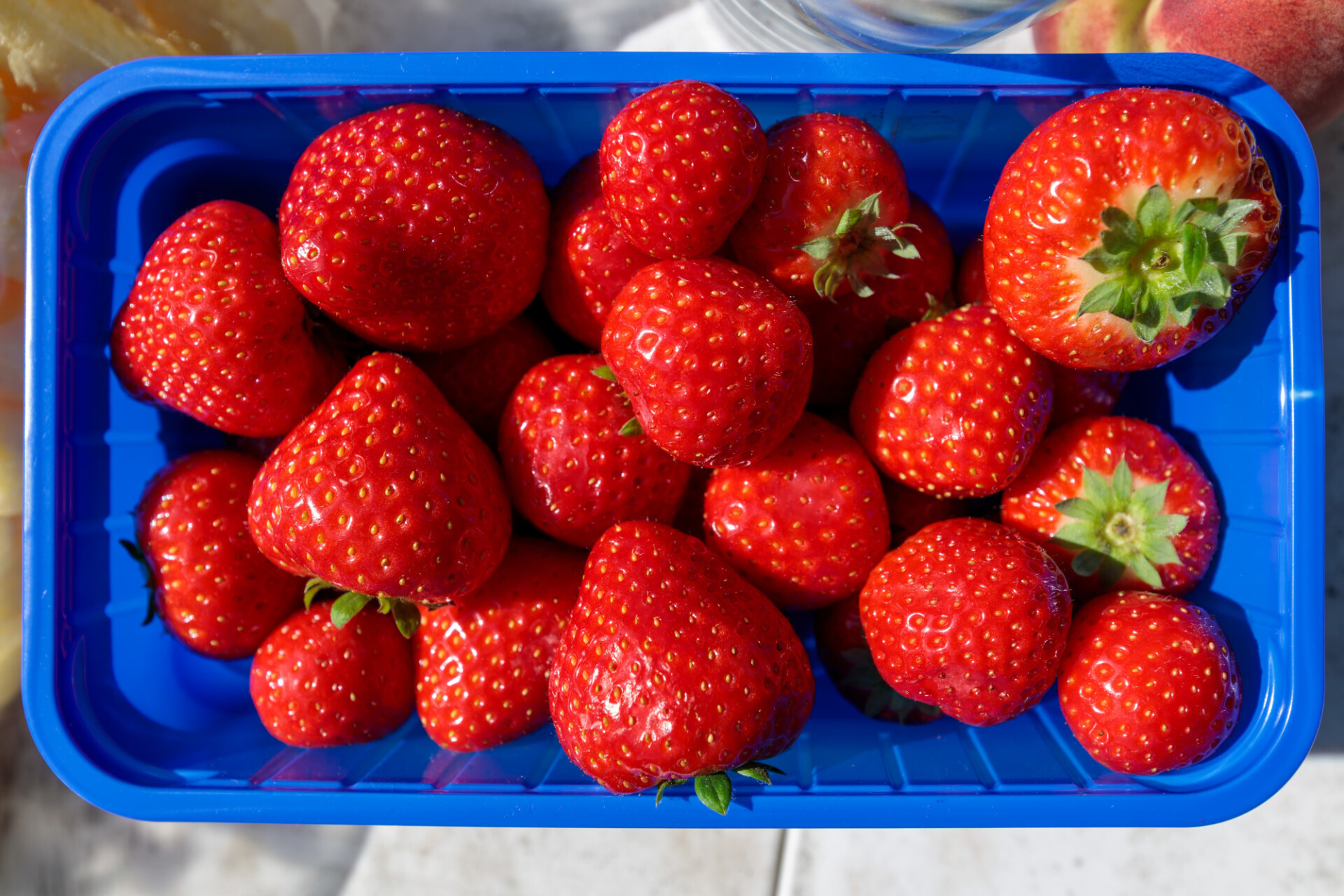 Strawberries from the supermarket in a blue plastic bowl