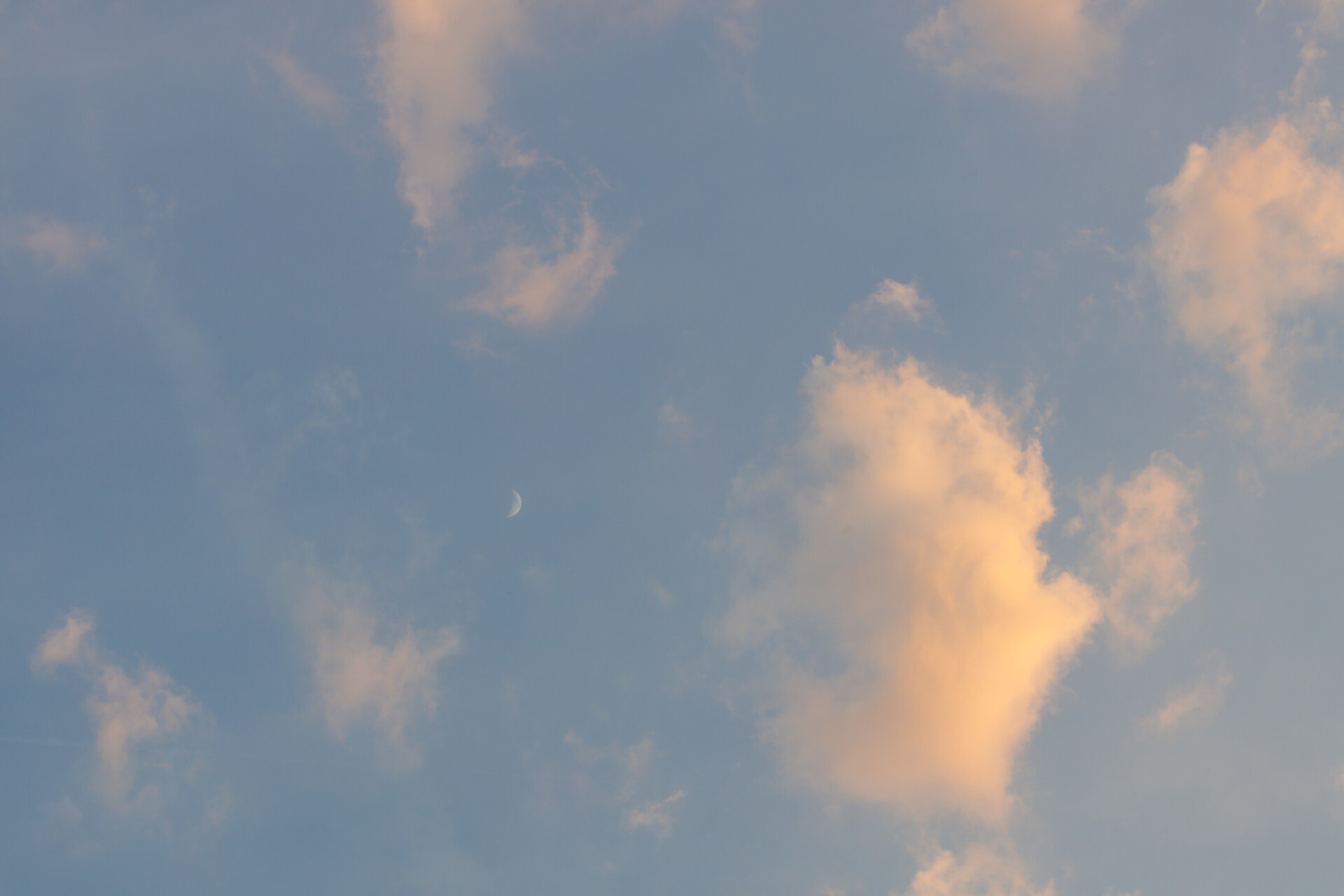 Horizontally photographed sky at evening time with clouds and the moon