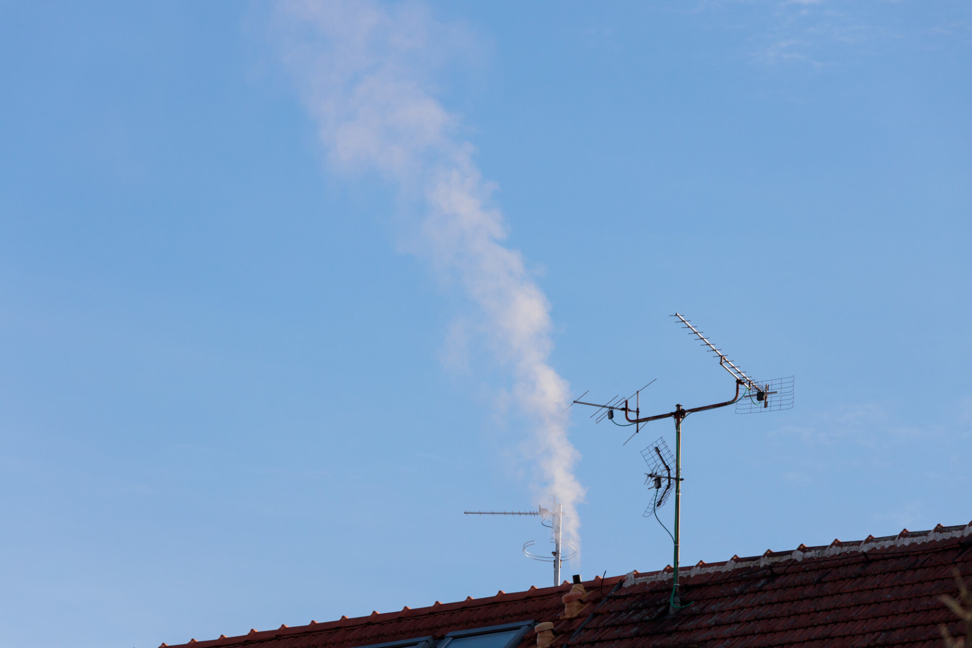Roof with antenna and chimney from which smoke comes out