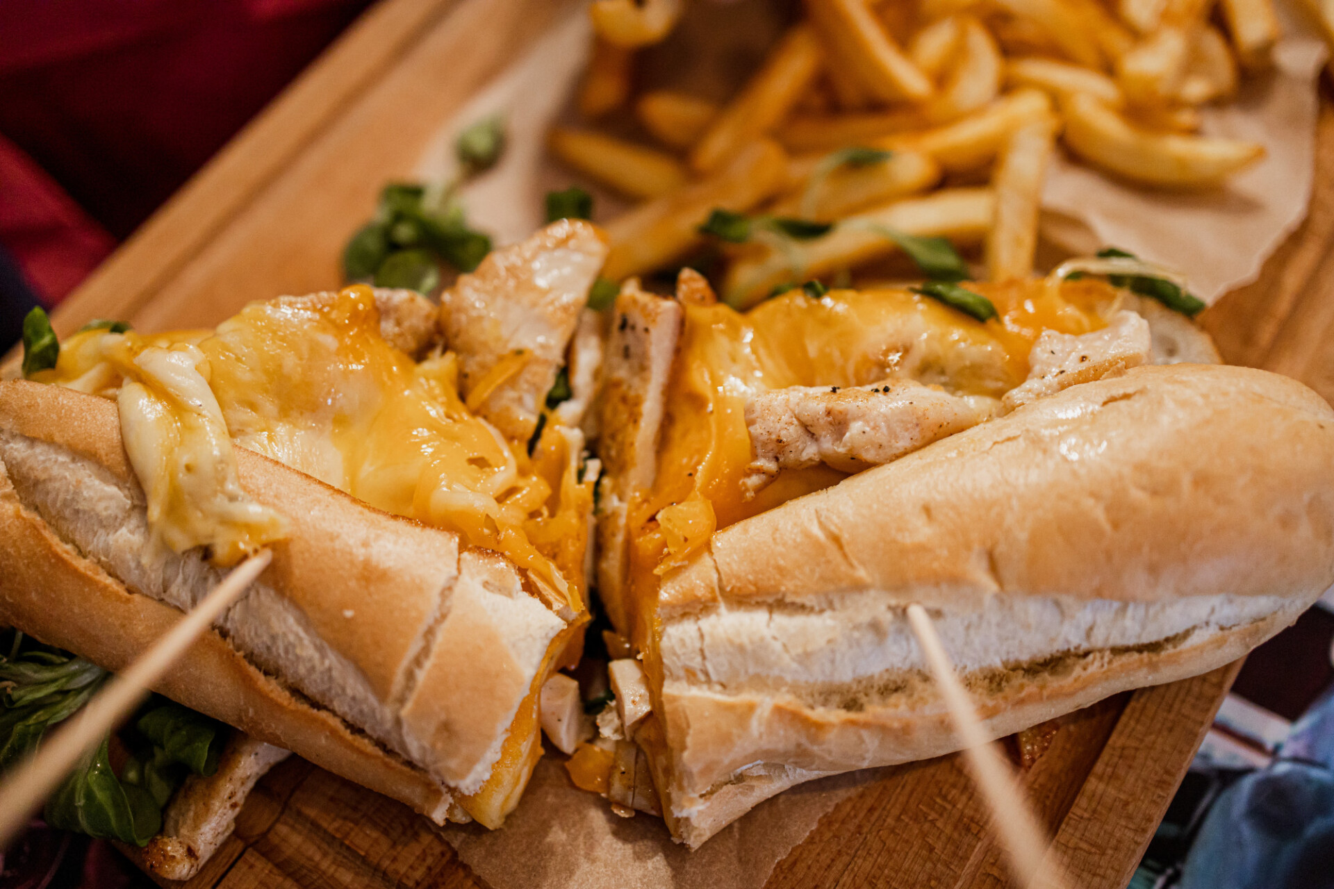 Baguette topped with melted cheese and chicken fillet served with fries