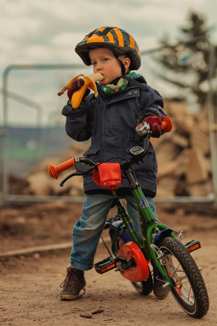 Little boy takes a bike break and eats a banana