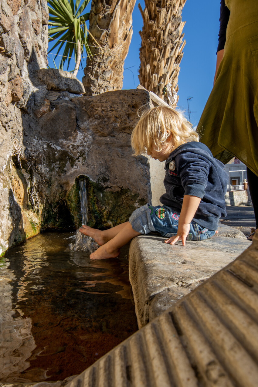 Little girl splashes her feet in a fountain