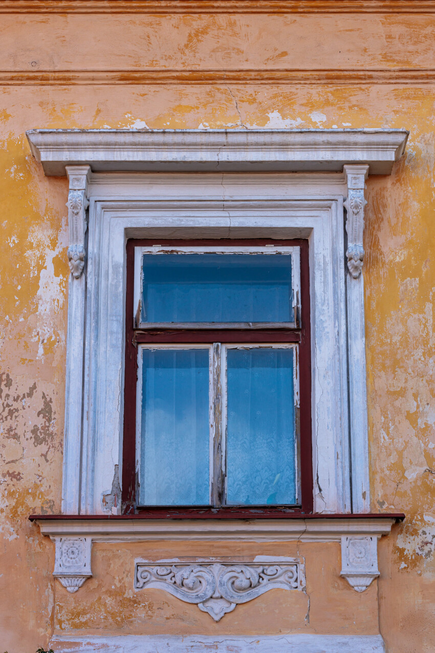 Old window in crumbling yellow wall