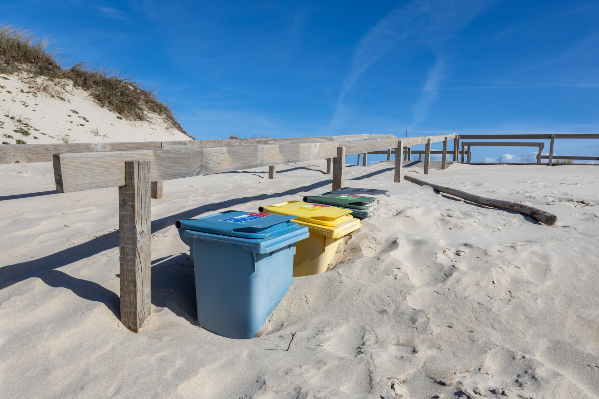 Rubbish bins sink into the sand dunes on the beach