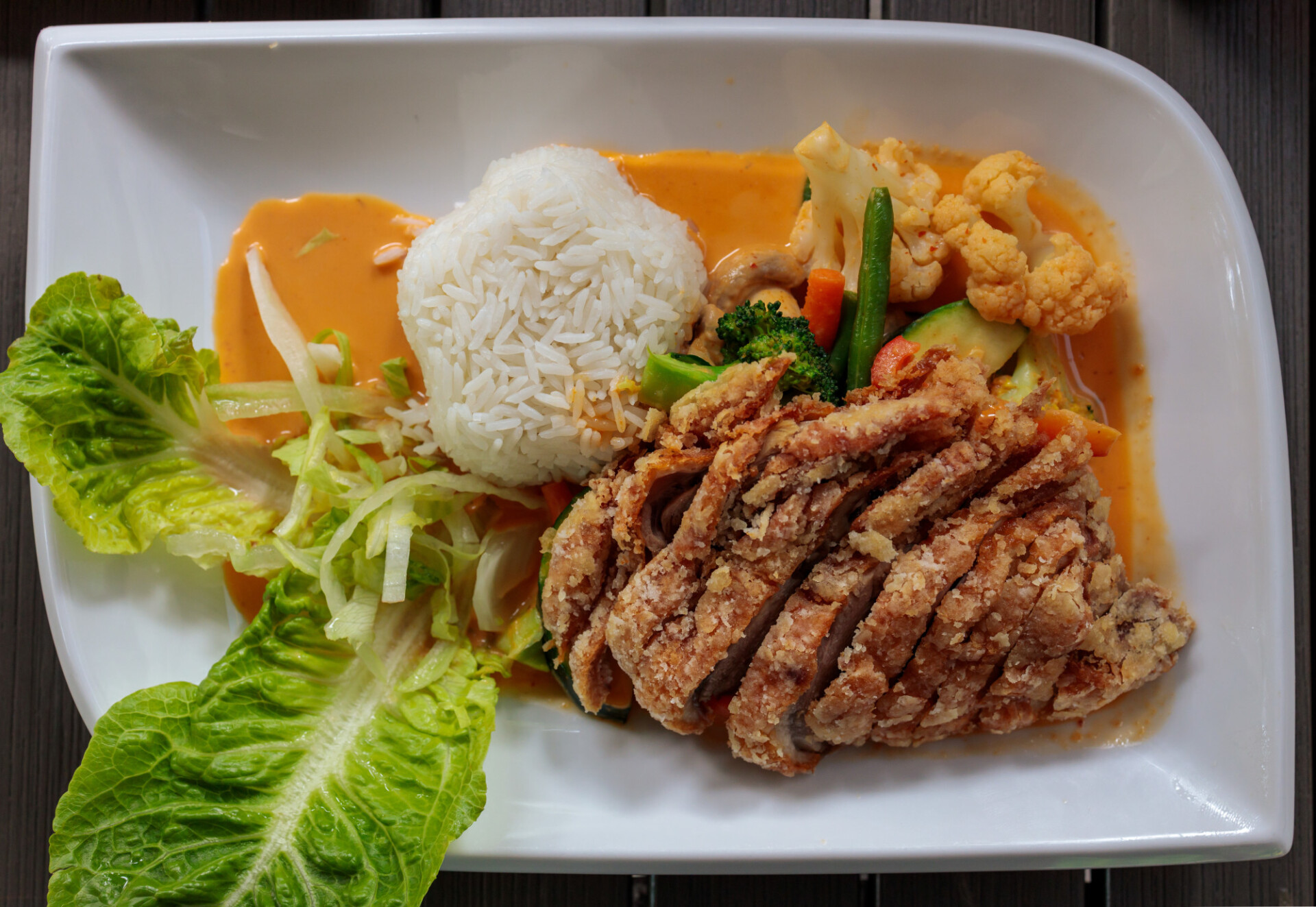 Asian crispy duck with vegetables, rice and curry sauce