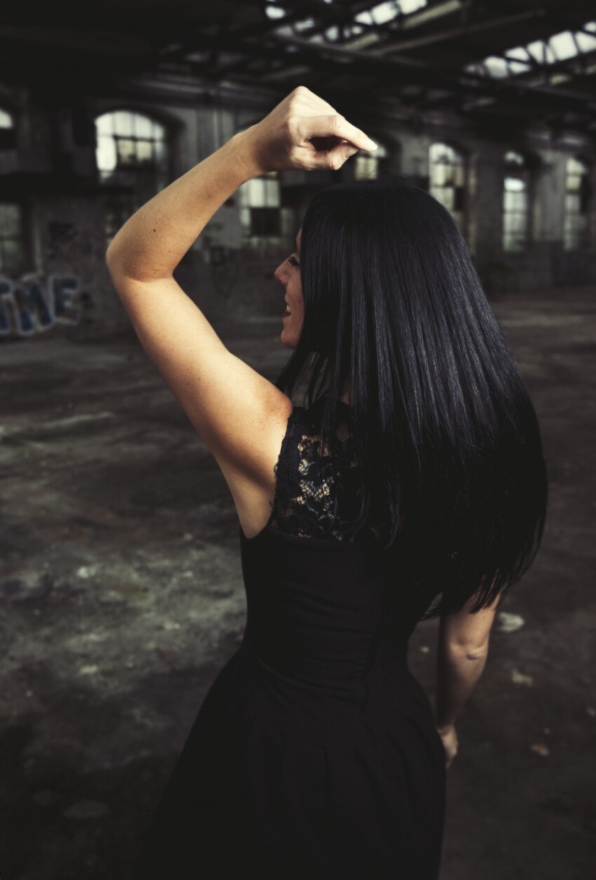 Woman in black dress is dancing in an old warehouse