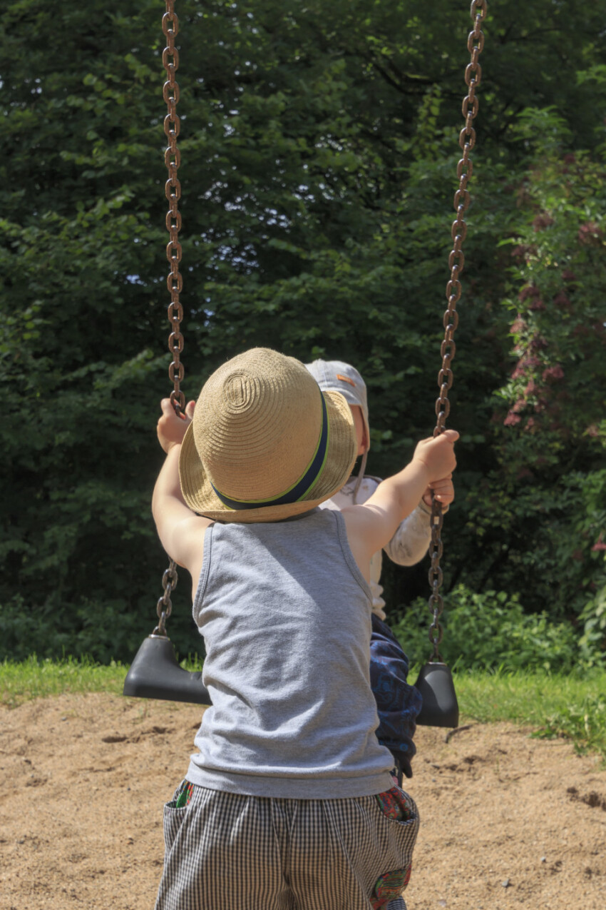 Big brother helps his little brother swing - children in toddler age