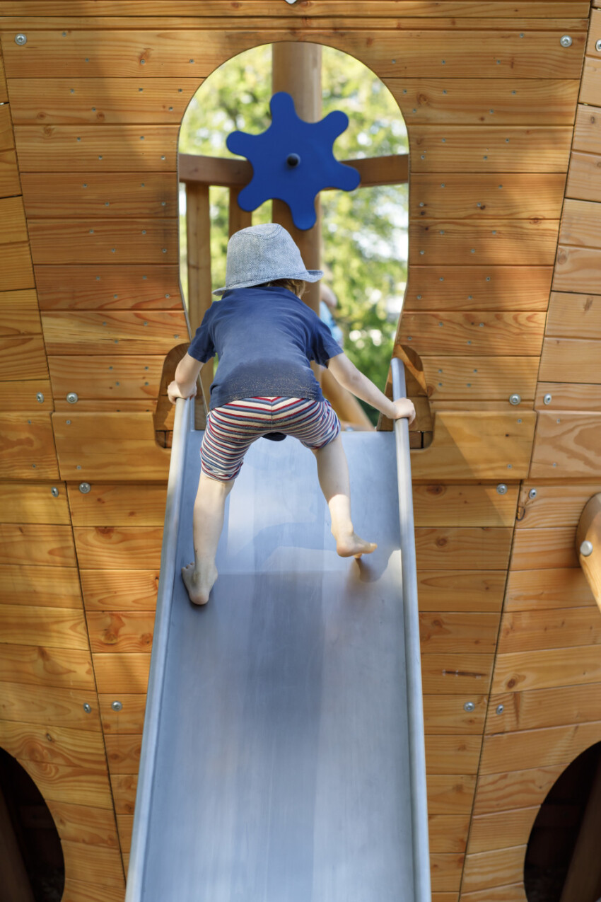 Little boy climbs up a slide on a playground