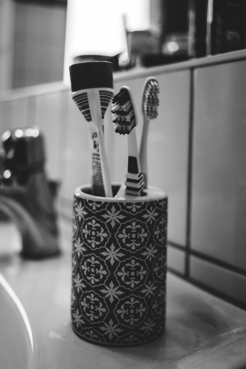 cup with toothbrushes and toothpaste in a bathroom