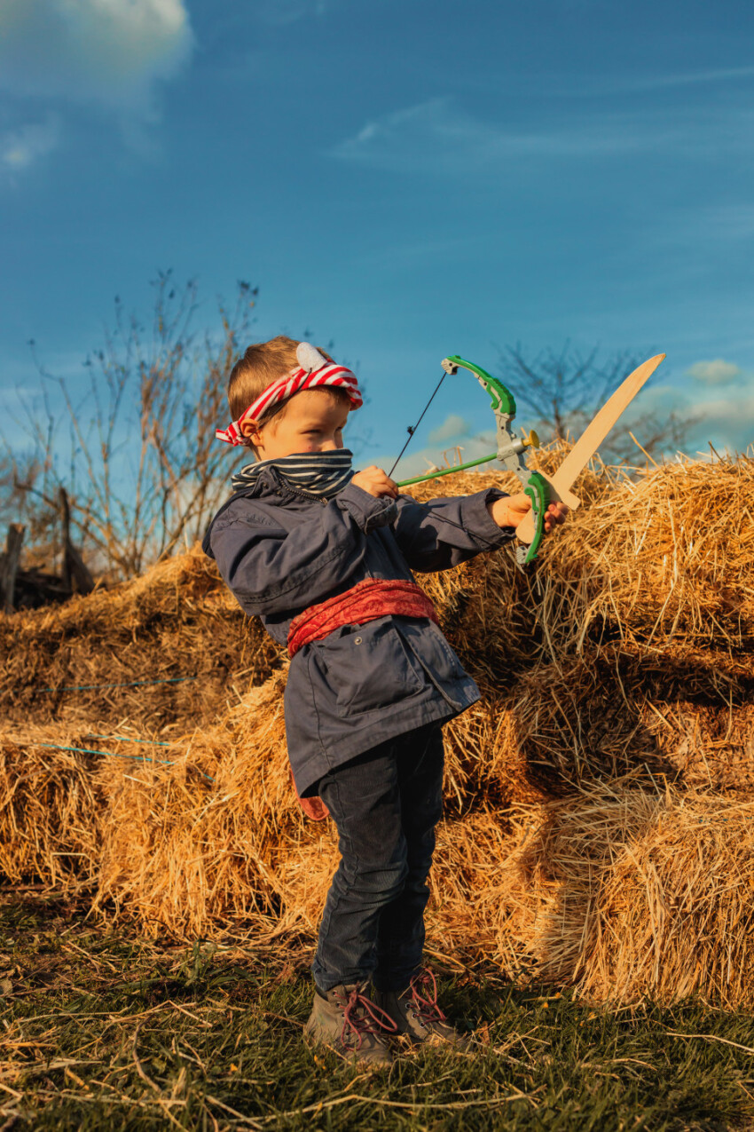 Little boy with wooden sword and bow plays pirate