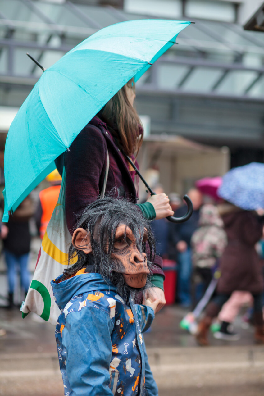 Child with monkey mask holding his mothers hand