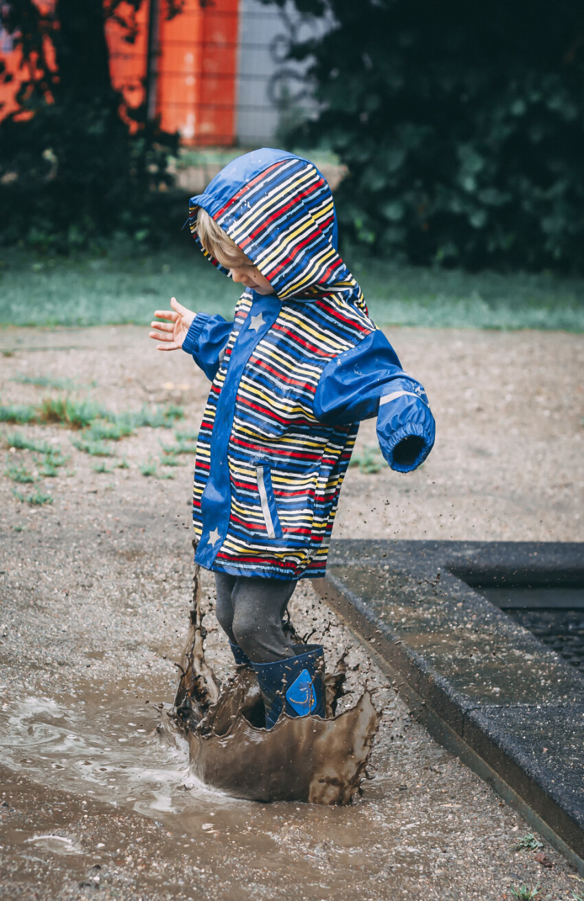 child jumps in a mud puddle