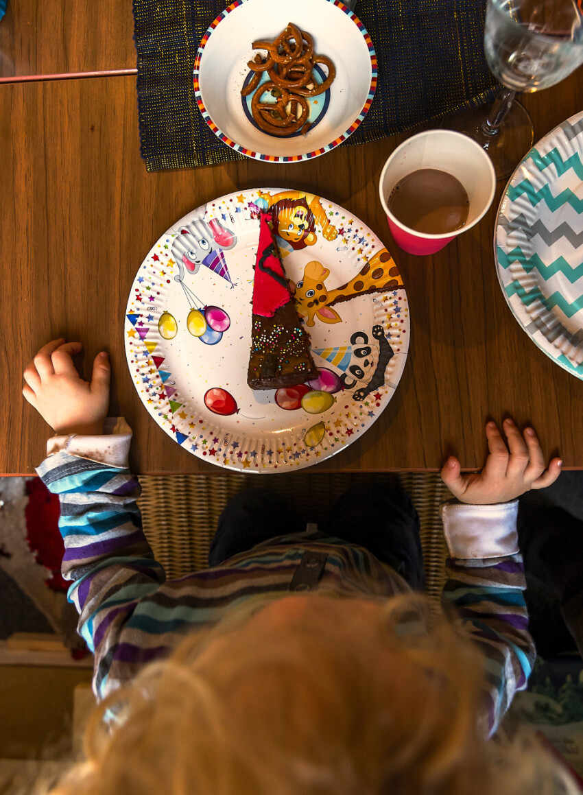 Chocolate cake on a paper plate in front of a child from above - birthday party