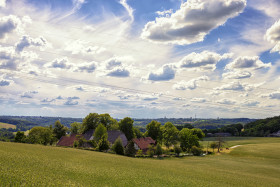 Stock Image: A beautiful organic farm in Germany under a blue sky with impressive clouds