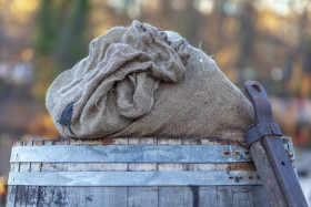 Stock Image: An ancient barrel in a harbor with a sack on it