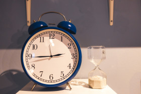 Stock Image: Blue alarm clock and sandglass