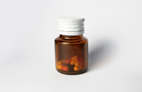 Stock Image: Brown glass bottle with vitamin or supplement product and white cap