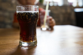 Stock Image: bubbly cola glass on wooden table