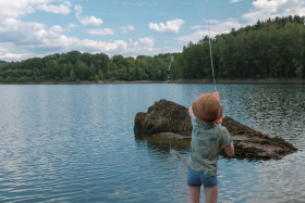 Stock Image: child is playing with a watergun on a lake  - landscape in germany nrw wuppertalsperre