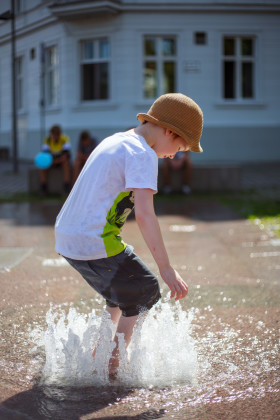 Stock Image: Child plays with the water from a fountain in summer