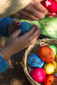 Stock Image: Children peel off the shell of colorful Easter eggs