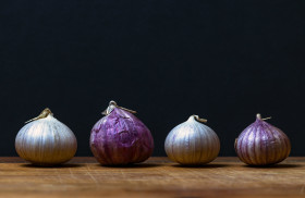 Stock Image: four garlic bulbs on a wooden board - black background