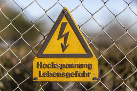 Stock Image: German High Voltage Sign close up shot on a chain-link fence