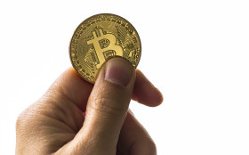 Stock Image: Isolated hand holding a golden bitcoin