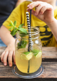 Stock Image: Little Child drink juice or ice tea or summer drink from glasses through straws