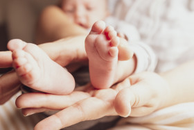 Stock Image: Newborn baby feet on female hands