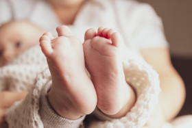 Stock Image: Newborn baby feet on female hands