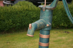Stock Image: Old green manual water pump in the garden