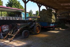 Stock Image: old green tractor with hay loaded trailer