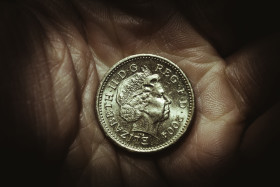 Stock Image: One British pound in a hand, money coin background