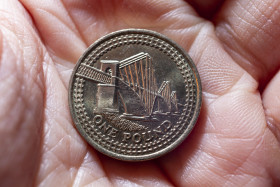 Stock Image: One British pound in a hand, money coin background