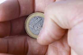 Stock Image: One euro coin in a hand isolated on a white background