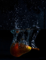 Stock Image: Pear falls into the water with lots of water splashes on a black background