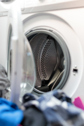 Stock Image: Pile of laundry in front of washing machine Photographed vertically
