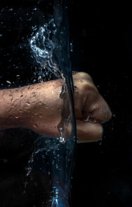 Stock Image: Power in hands - A fist strikes through water