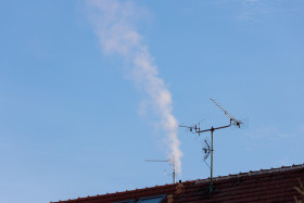 Stock Image: Roof with antenna and chimney from which smoke comes out
