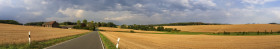 Stock Image: Stormy clouds are gathering over a rural landscape with a Farm and a country road between fields in Germany near Velbert Langenberg, Neviges in North Rhine Westphalia