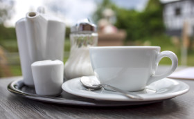 Stock Image: white cup of coffee on a table in a restaurant